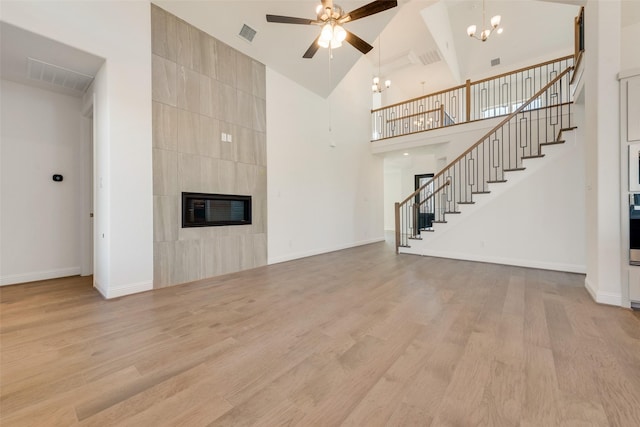 3542 Coneflower Trl, Prairie Ridge, TX 76084 - unfurnished living room featuring ceiling fan, a tile fireplace, a chandelier, stairs, and high vaulted ceiling