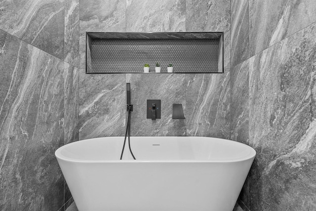 bathroom featuring a bath and tile walls