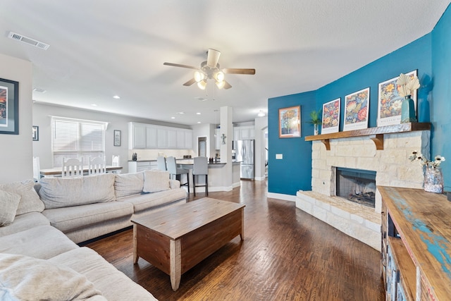 living room featuring a fireplace, dark wood-type flooring, and ceiling fan