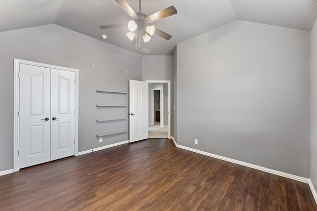 unfurnished bedroom with dark wood-type flooring, a closet, ceiling fan, and vaulted ceiling