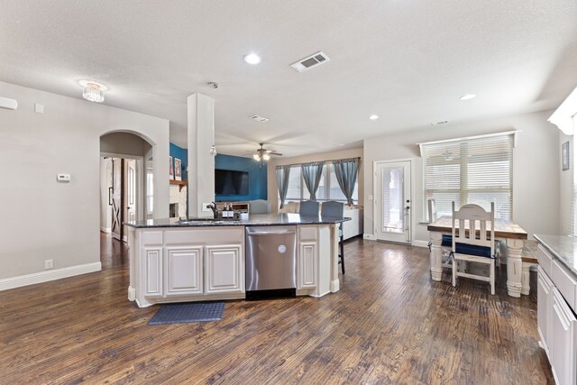 kitchen with stainless steel dishwasher, sink, white cabinetry, and a kitchen island with sink