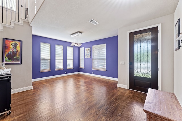 foyer entrance with dark hardwood / wood-style flooring and a textured ceiling