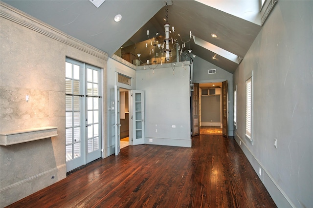 unfurnished room featuring dark wood-type flooring, high vaulted ceiling, french doors, a skylight, and a chandelier