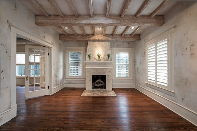 unfurnished living room with beam ceiling, dark hardwood / wood-style flooring, a fireplace, and a wealth of natural light