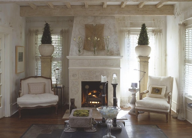 sitting room with a fireplace, beamed ceiling, and dark wood-type flooring