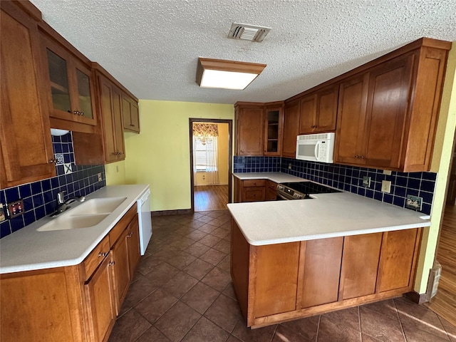 kitchen with sink, white appliances, kitchen peninsula, and backsplash