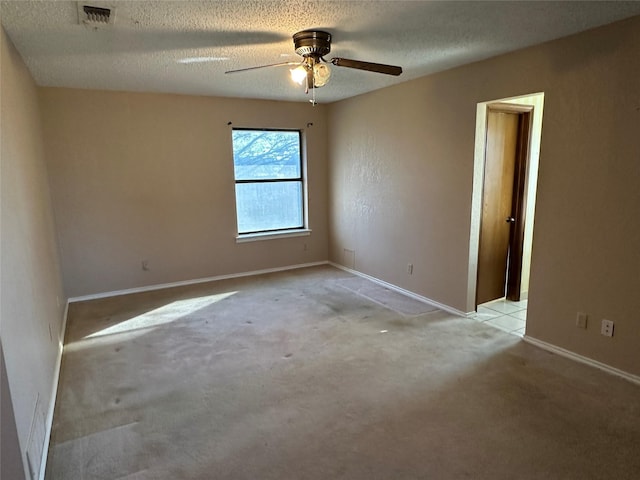 spare room featuring ceiling fan, light colored carpet, and a textured ceiling