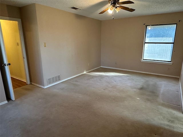 carpeted spare room featuring ceiling fan and a textured ceiling