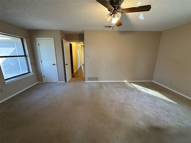 carpeted spare room featuring ceiling fan and a textured ceiling