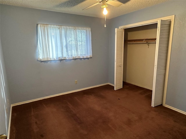 unfurnished bedroom with ceiling fan, a closet, a textured ceiling, and dark colored carpet