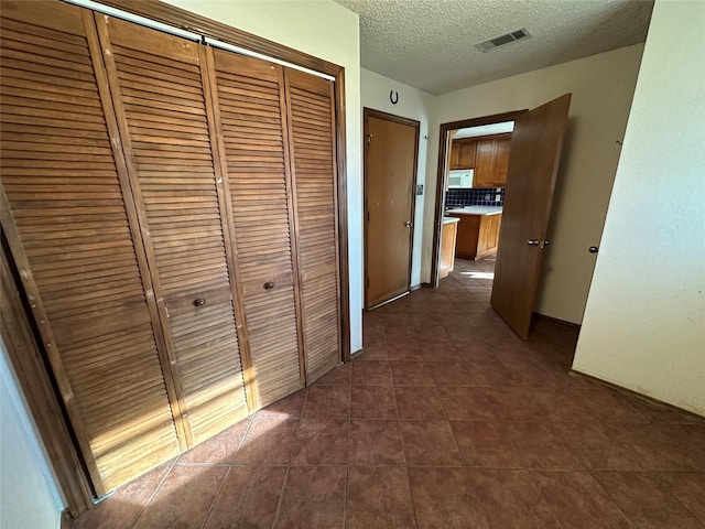 hallway featuring dark tile patterned floors and a textured ceiling