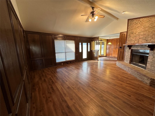 unfurnished living room featuring ceiling fan, a fireplace, a textured ceiling, dark hardwood / wood-style flooring, and beamed ceiling