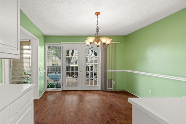 unfurnished dining area with dark hardwood / wood-style floors, a wealth of natural light, and a notable chandelier