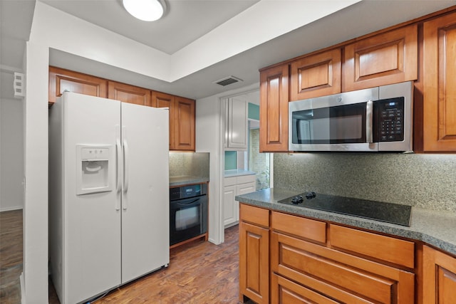 kitchen featuring tasteful backsplash, wood-type flooring, and black appliances