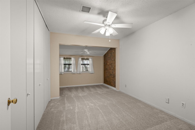 empty room featuring light carpet, ceiling fan, and a textured ceiling