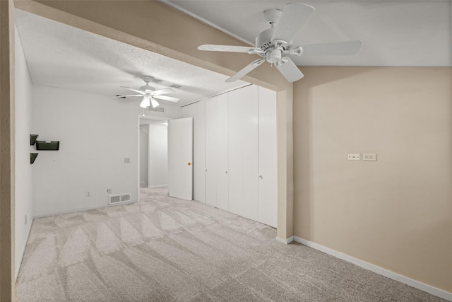 empty room featuring ceiling fan, light carpet, and a textured ceiling