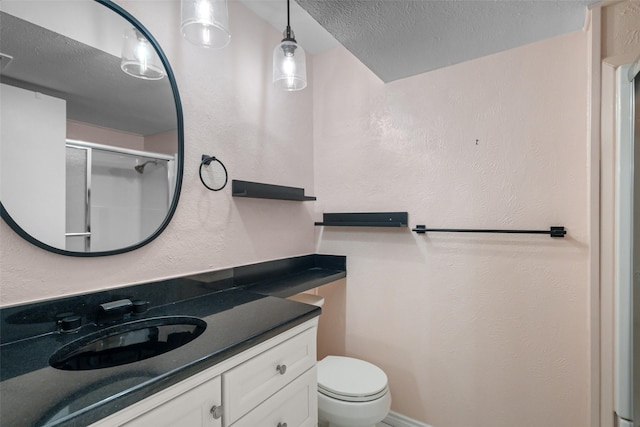 bathroom featuring a shower with door, vanity, a textured ceiling, and toilet