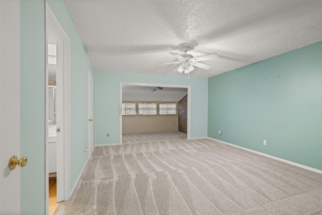 carpeted spare room with a textured ceiling and ceiling fan