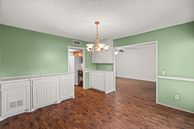 unfurnished dining area featuring a chandelier, a textured ceiling, and dark hardwood / wood-style flooring