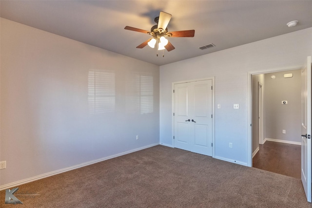 unfurnished bedroom with dark carpet, vaulted ceiling, a closet, and ceiling fan