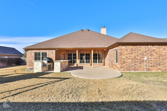 back of house featuring an outdoor kitchen, a yard, and a patio area