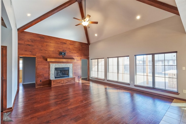 unfurnished living room with beamed ceiling, a tile fireplace, dark hardwood / wood-style flooring, and wood walls