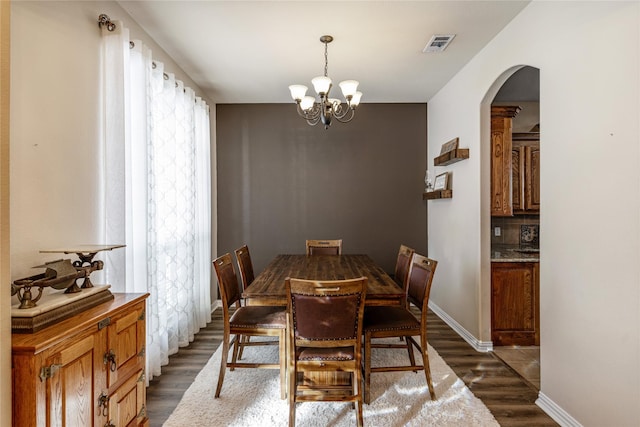 dining room with an inviting chandelier and dark wood-type flooring