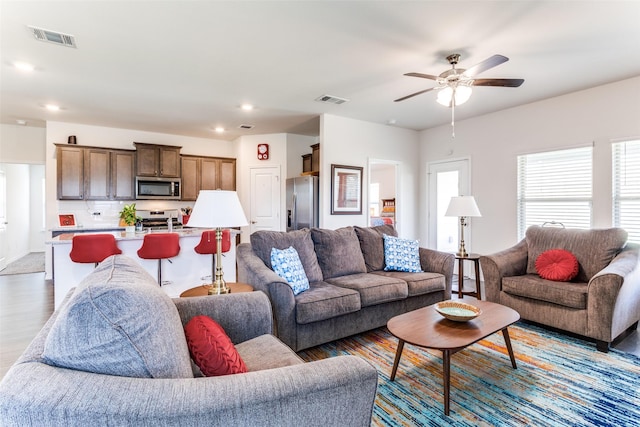 living room with ceiling fan, a healthy amount of sunlight, and light hardwood / wood-style floors