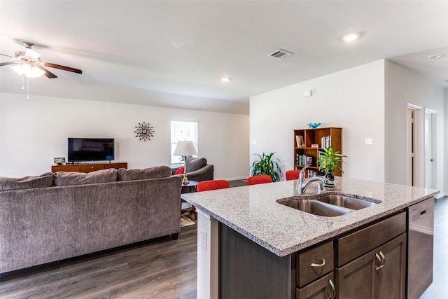 kitchen featuring dark hardwood / wood-style flooring, stainless steel dishwasher, dark brown cabinets, a kitchen island with sink, and sink