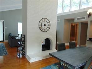 dining area with a fireplace, wood-type flooring, and a towering ceiling