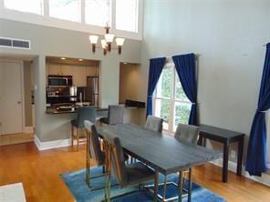 dining space featuring a chandelier, hardwood / wood-style floors, and a towering ceiling