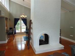 living room with a chandelier, wood-type flooring, vaulted ceiling, and a multi sided fireplace