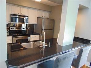 kitchen with white cabinets, a kitchen breakfast bar, sink, kitchen peninsula, and stainless steel appliances