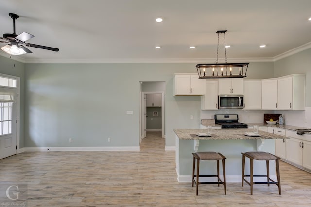 kitchen featuring light stone counters, white cabinetry, a kitchen island, and appliances with stainless steel finishes