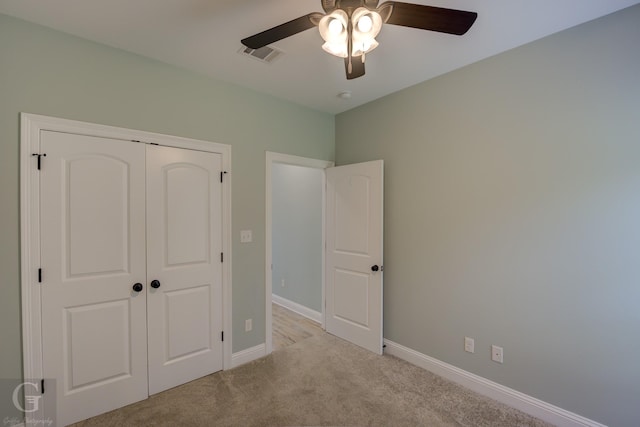 unfurnished bedroom with light colored carpet, a closet, and ceiling fan