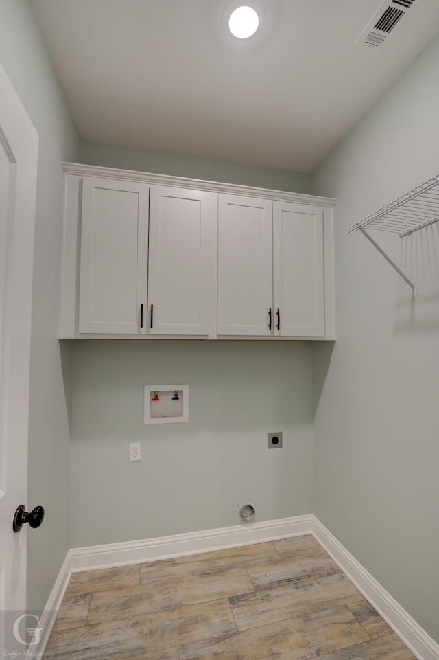 laundry area with electric dryer hookup, washer hookup, cabinets, and light wood-type flooring