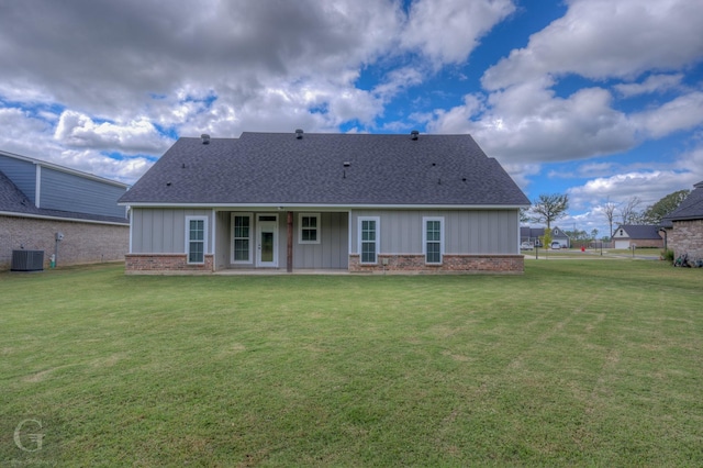 rear view of property featuring central AC unit and a lawn