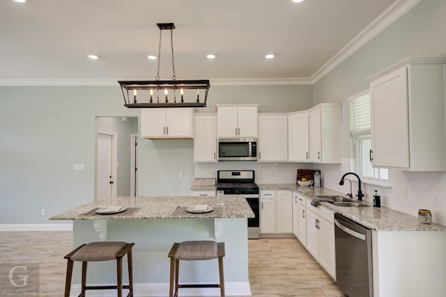 kitchen featuring white cabinetry, sink, a center island, stainless steel appliances, and light stone countertops