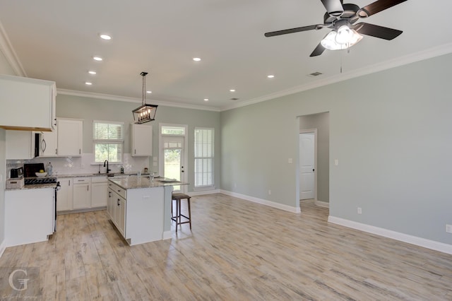 kitchen with light stone countertops, a center island, white cabinets, and decorative light fixtures