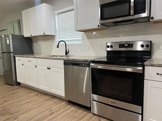 kitchen with light stone countertops, white cabinetry, appliances with stainless steel finishes, and sink