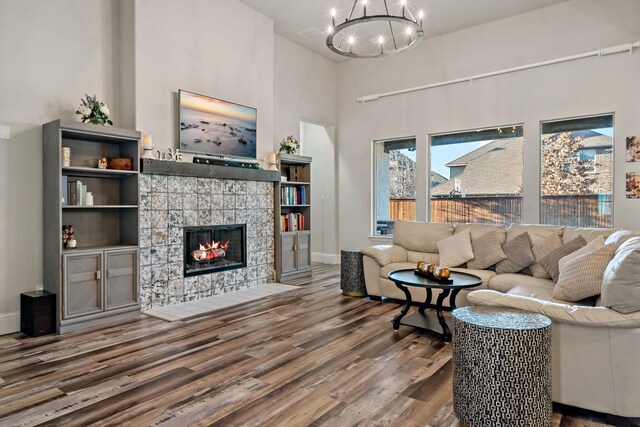 living room with a tile fireplace, wood-type flooring, and a notable chandelier