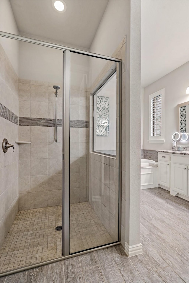 bathroom with hardwood / wood-style flooring, vanity, and shower with separate bathtub