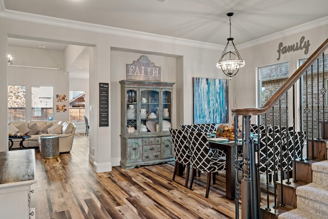 dining room with ornamental molding, wood-type flooring, and a notable chandelier