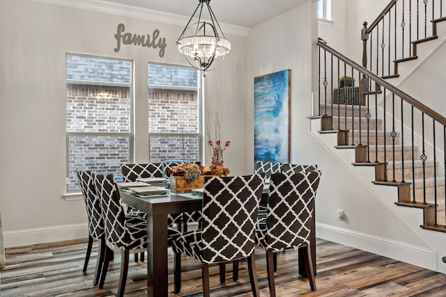 dining room with wood-type flooring, a chandelier, and crown molding