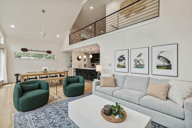 living room with sink, wood-type flooring, ceiling fan, and a high ceiling