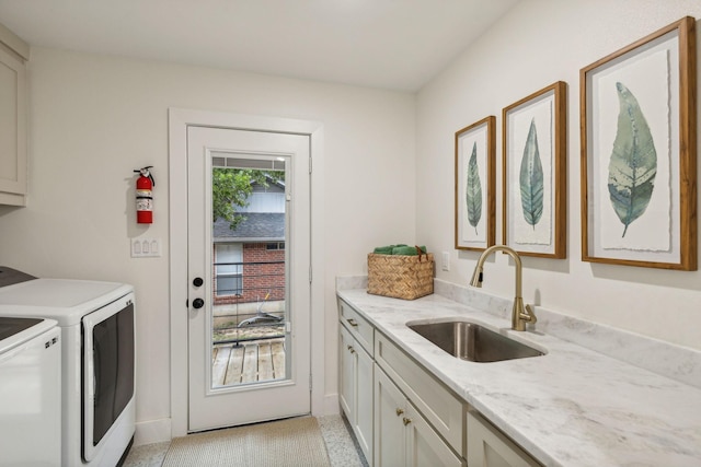 clothes washing area featuring cabinets, sink, and independent washer and dryer