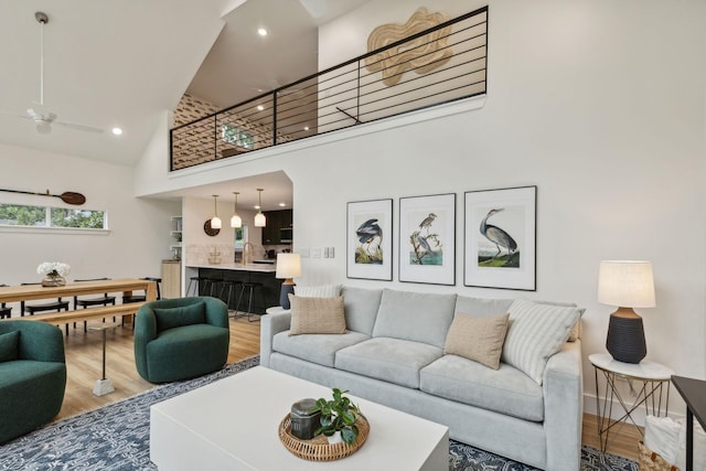 living room featuring hardwood / wood-style flooring, ceiling fan, sink, and a high ceiling