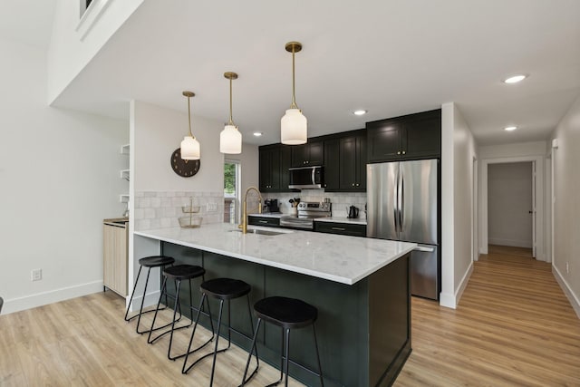 kitchen featuring pendant lighting, sink, stainless steel appliances, a kitchen bar, and kitchen peninsula