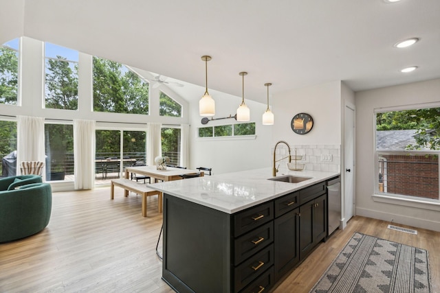 kitchen featuring sink, dishwasher, hanging light fixtures, light stone countertops, and light wood-type flooring