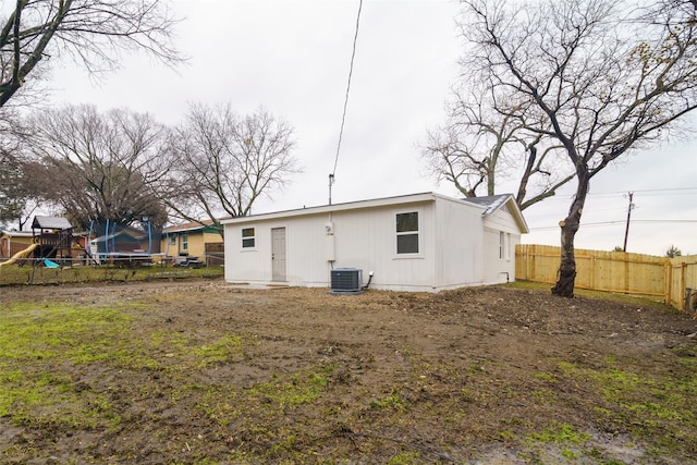 rear view of house featuring cooling unit, a trampoline, and a playground